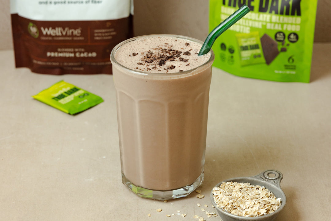 cup-of-chocolate-oat-protein-smoothie-with-wellvine-and-vine-to-bar-bags-in-background